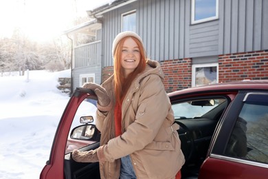Beautiful young woman getting out of car. Winter vacation