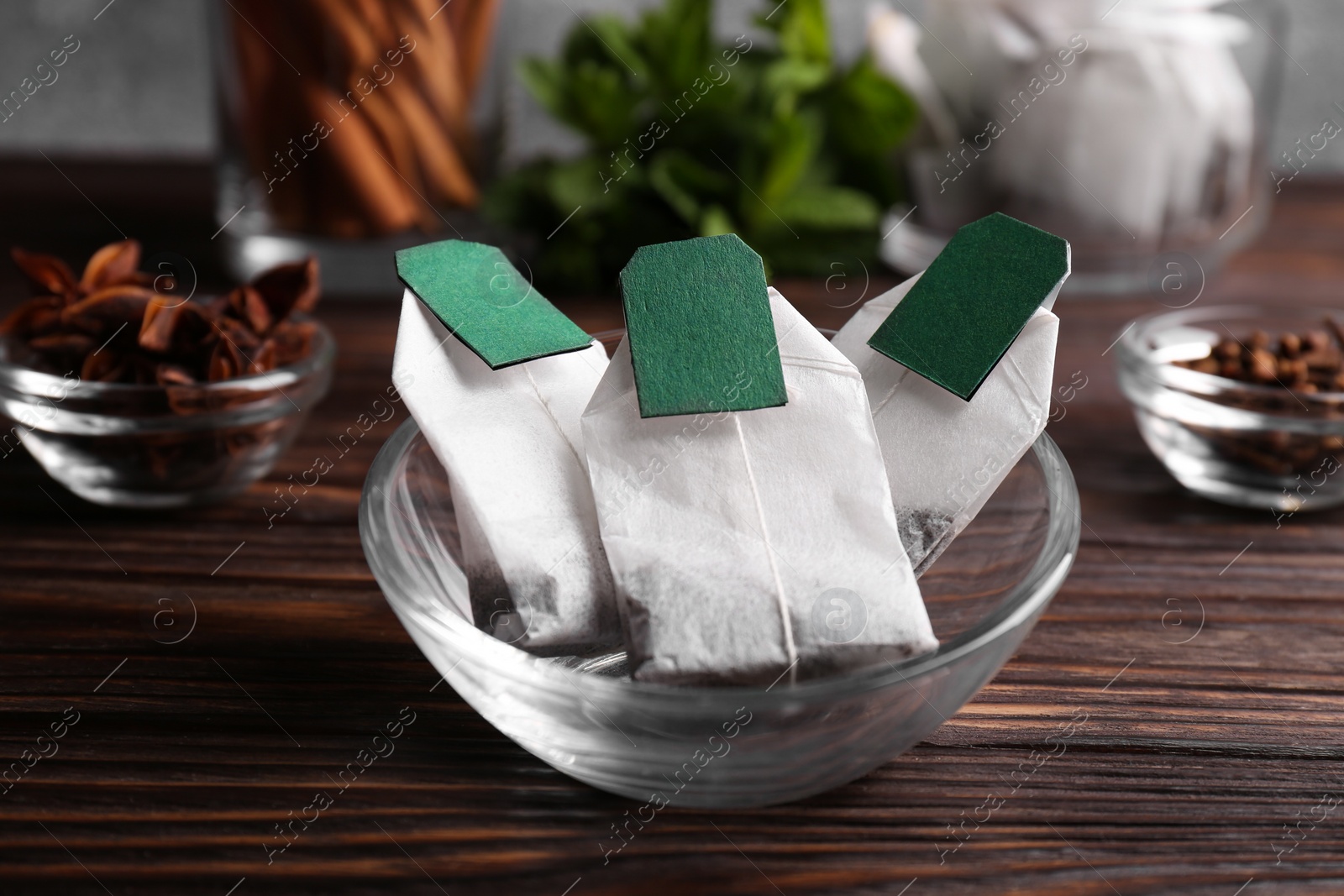 Photo of Tea bags and ingredients on wooden table, closeup