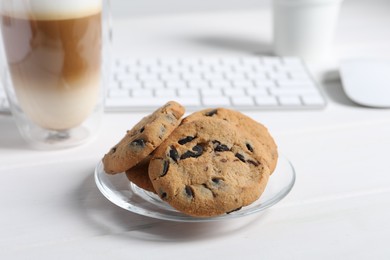 Photo of Chocolate chip cookies on white wooden table at workplace