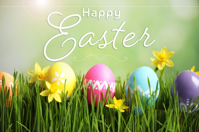 Colorful eggs and daffodil flowers in green grass and text Happy Easter on blurred background