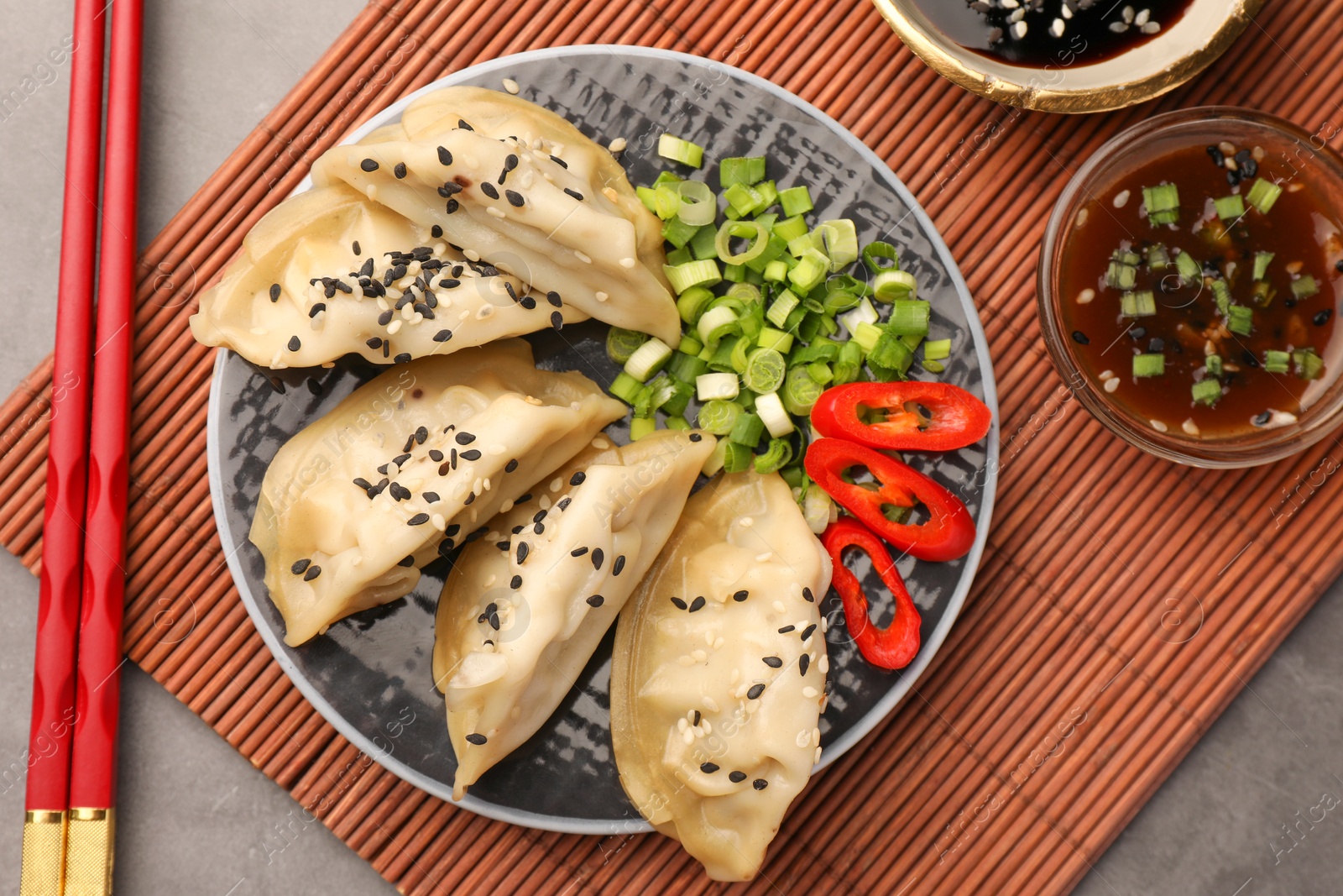 Photo of Delicious gyoza (asian dumplings) served on gray table, flat lay