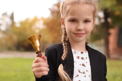 Photo of Pupil with school bell outdoors on sunny day