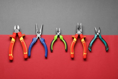 Different pliers on color background, flat lay