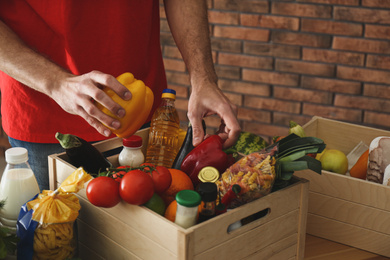 Photo of Man with fresh products at table indoors, closeup. Food delivery service