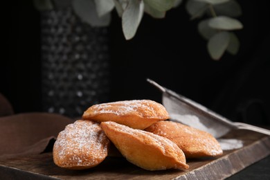 Photo of Delicious madeleine cakes with powdered sugar on table, closeup