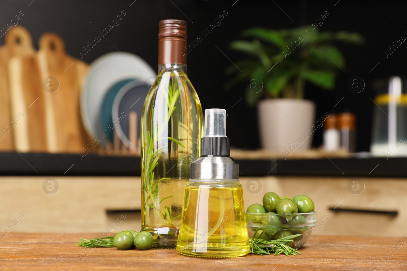 Photo of Olives, rosemary and cooking oil on wooden table in kitchen