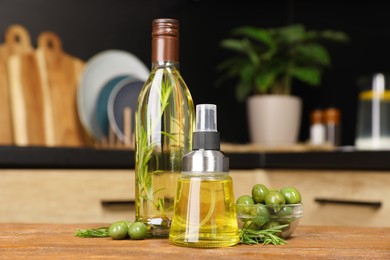 Olives, rosemary and cooking oil on wooden table in kitchen