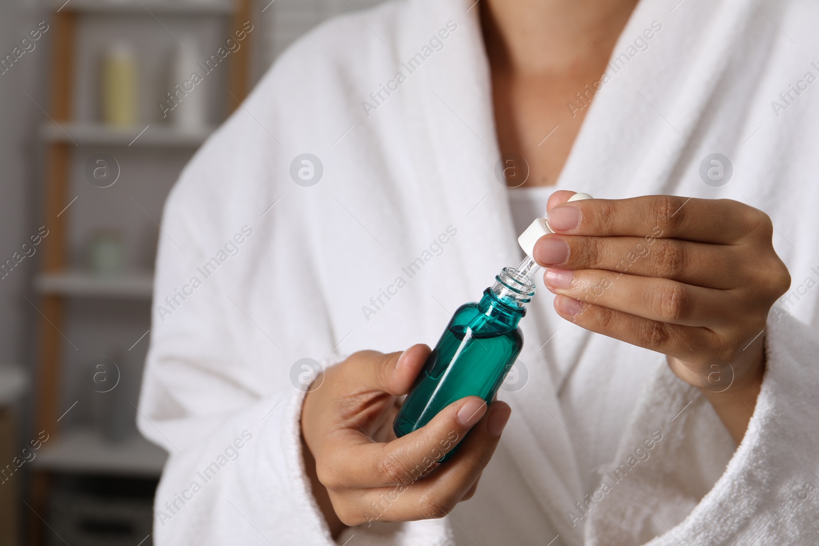 Photo of Woman with bottle of cosmetic serum and dropper on blurred background, closeup