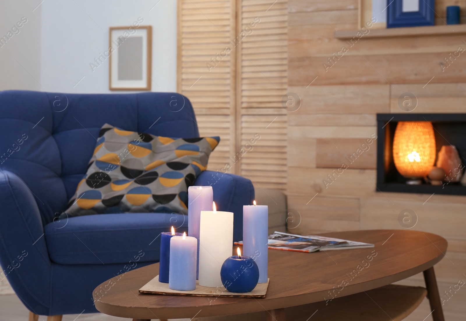 Photo of Burning candles on table in living room