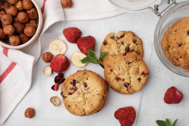 Photo of Cookies with freeze dried fruits, nuts and mint on white table, flat lay