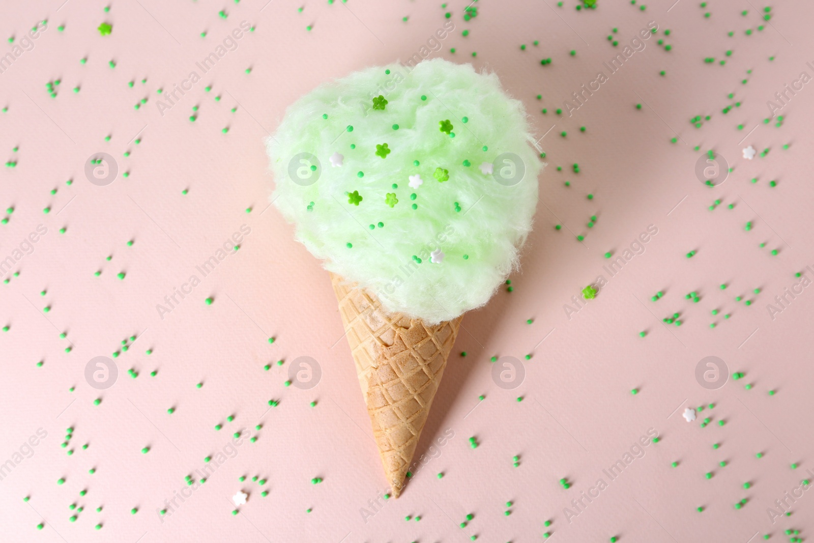 Photo of Sweet cotton candy in waffle cone on beige background, top view