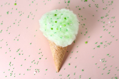 Photo of Sweet cotton candy in waffle cone on beige background, top view