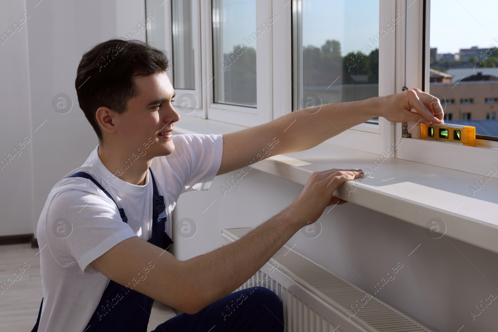 Photo of Worker using bubble level after plastic window installation indoors
