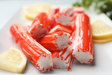 Photo of Delicious crab sticks with lemon on plate, closeup
