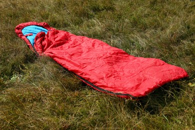 Photo of Red sleeping bag on green grass outdoors