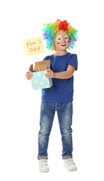 Little boy with clown makeup holding April fool's day sign on white background