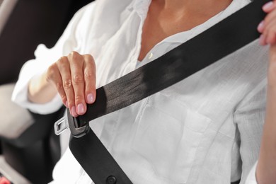 Photo of Woman pulling seat belt in car, closeup