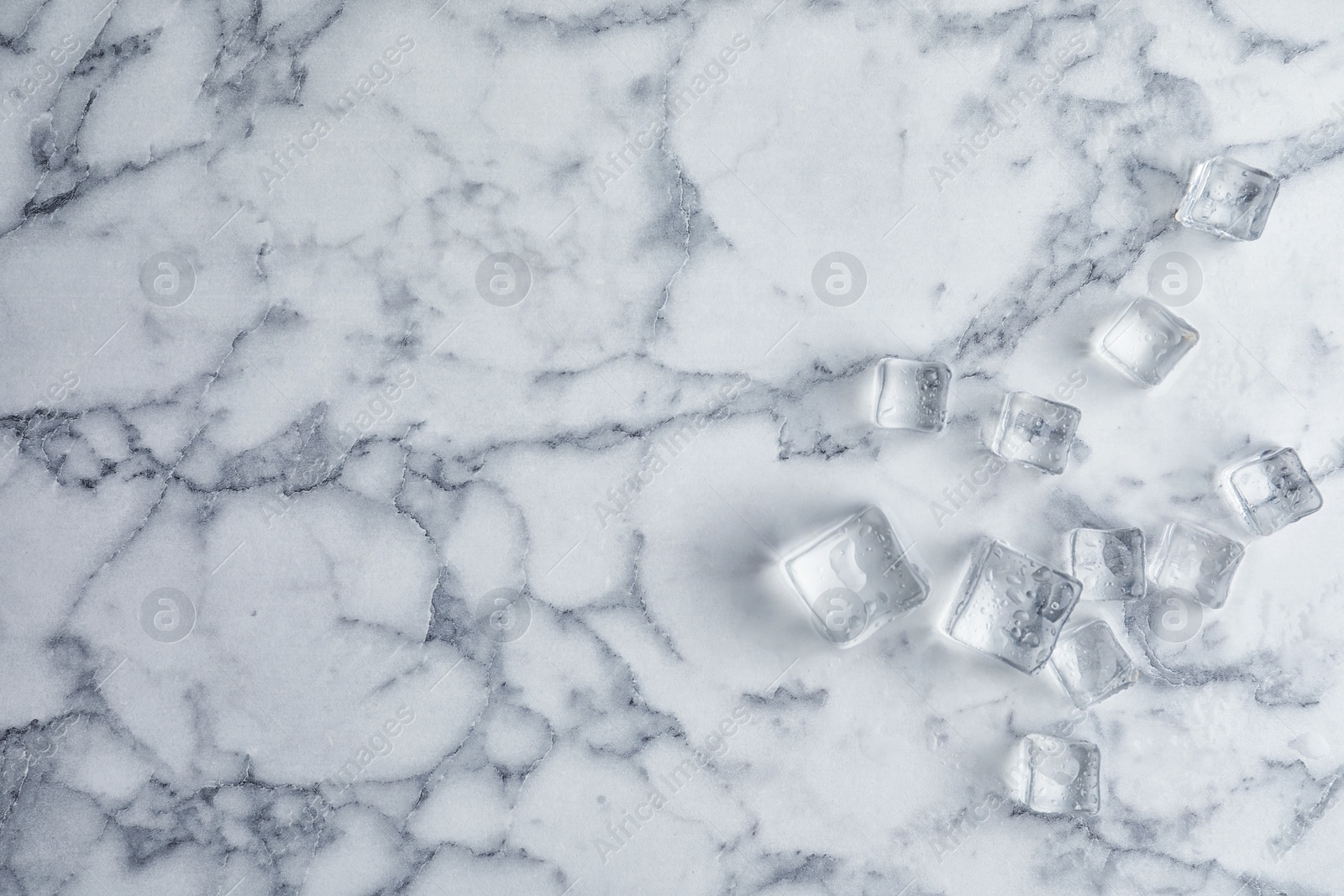 Photo of Crystal clear ice cubes with water drops on white marble table, flat lay. Space for text