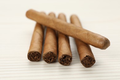 Photo of Cigars wrapped in tobacco leaves on white wooden table, closeup