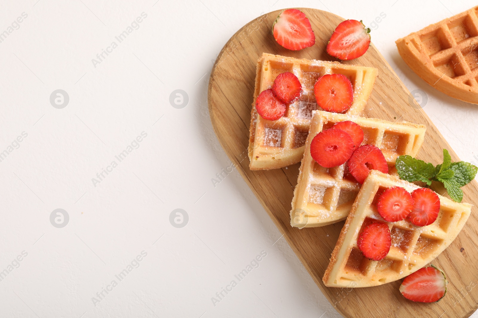 Photo of Tasty Belgian waffles with strawberries and mint on white table, flat lay. Space for text