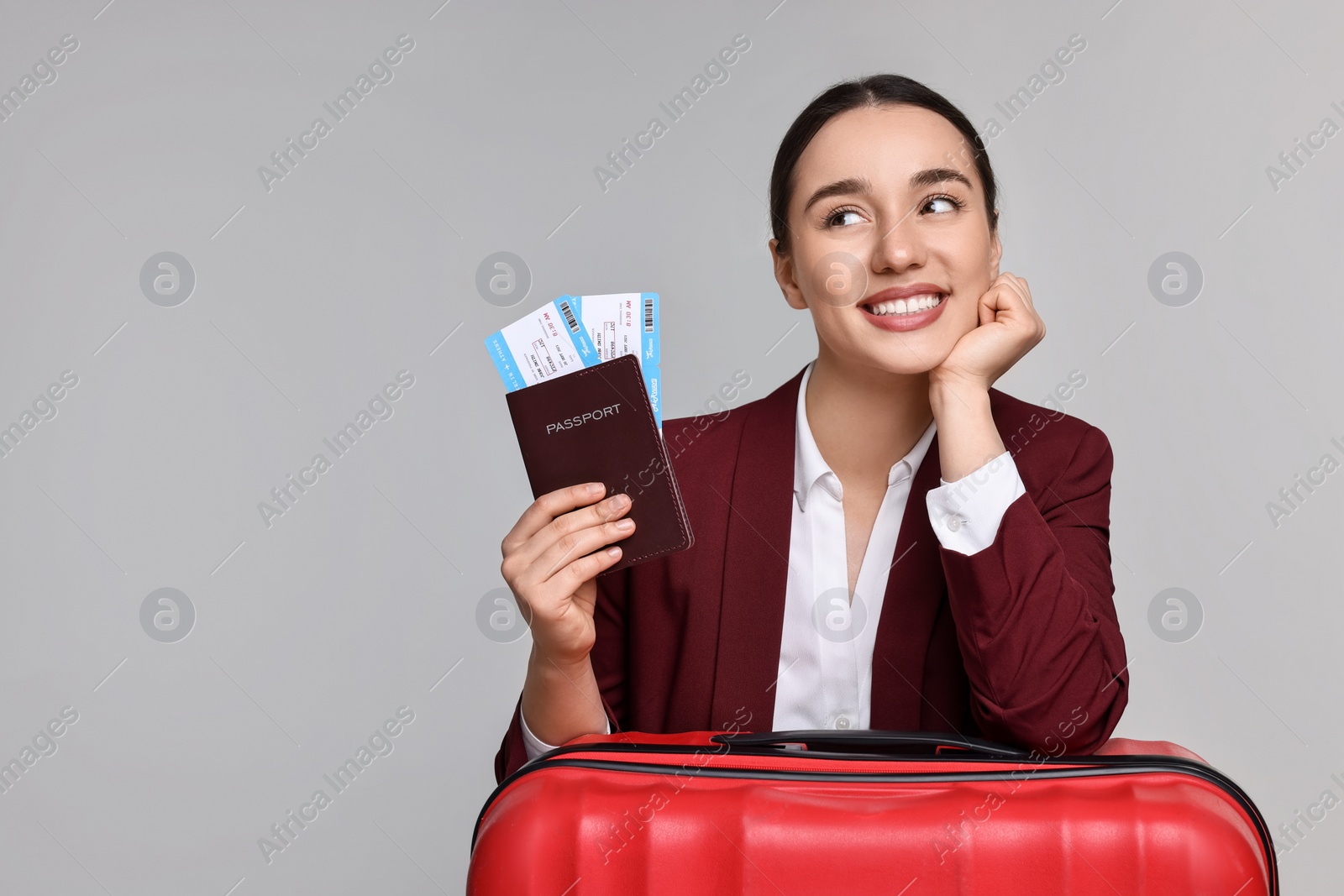 Photo of Happy businesswoman with passport, tickets and suitcase on grey background. Space for text