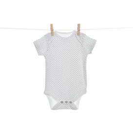 Baby onesie hanging on clothes line against white background. Laundry day