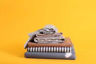 Photo of Stack of clean bed sheets on yellow background