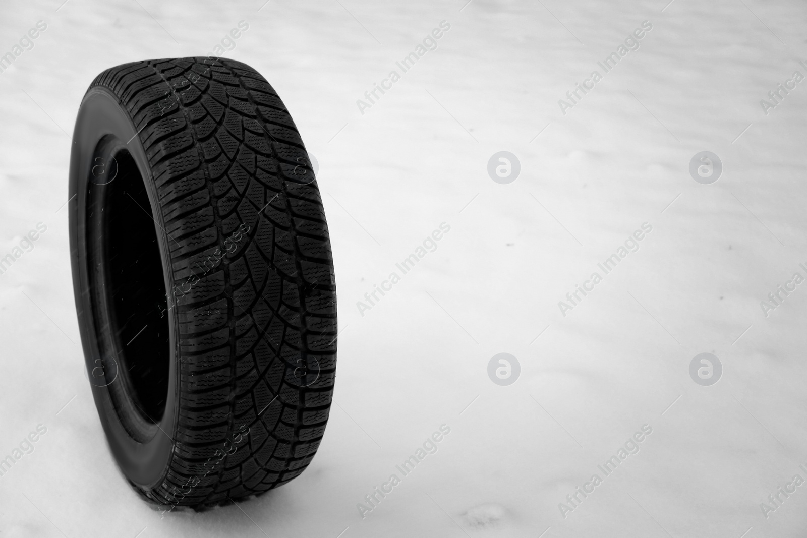 Photo of New winter tire on fresh snow. Space for text