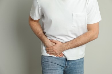 Photo of Man suffering from acute appendicitis on light grey background, closeup