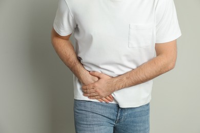 Man suffering from acute appendicitis on light grey background, closeup