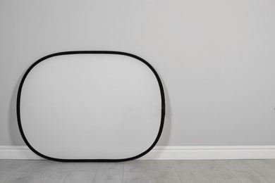 Photo of Studio reflector near grey wall in room, space for text. Professional photographer's equipment