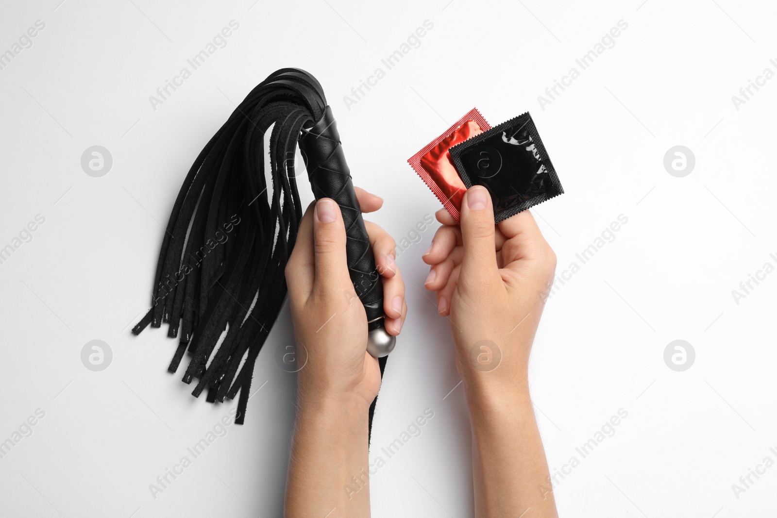 Photo of Woman with whip and condoms on white background, top view. Sex game