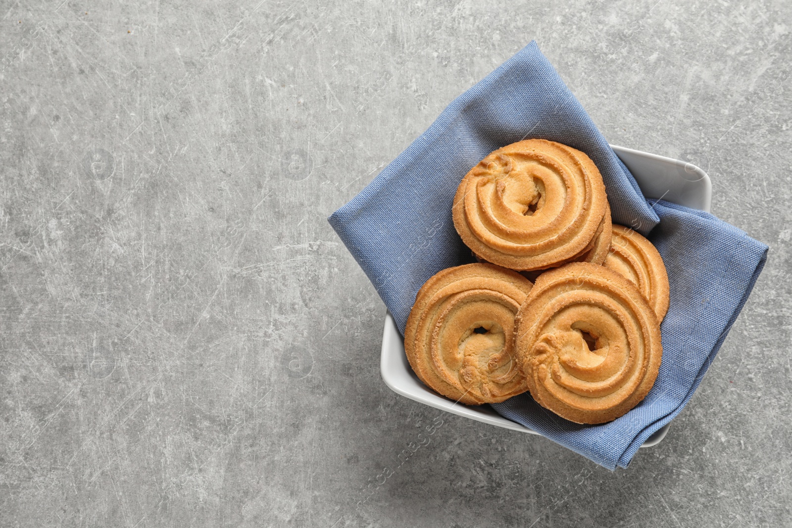 Photo of Bowl with Danish butter cookies on grey table, top view. Space for text