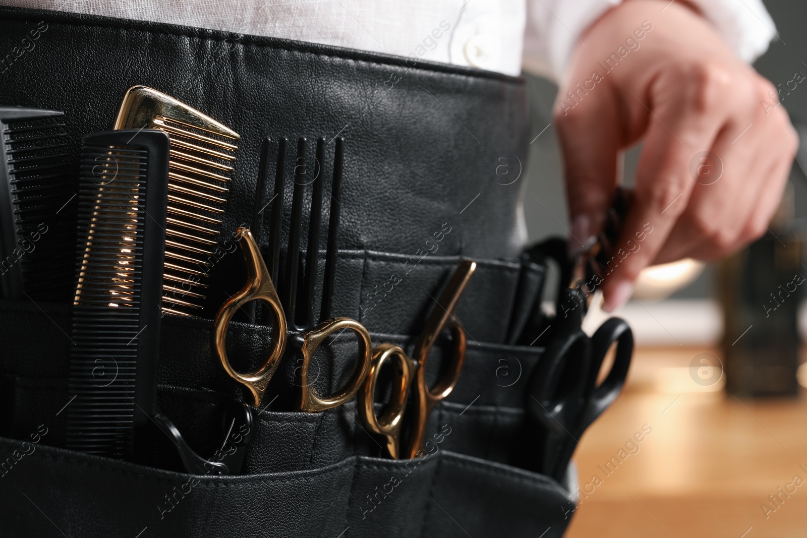 Photo of Hairstylist with professional tools in waist pouch in salon, closeup