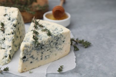 Tasty blue cheese with thyme on grey table, closeup. Space for text