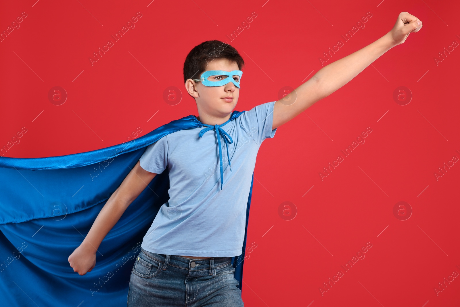 Photo of Teenage boy in superhero costume on red background