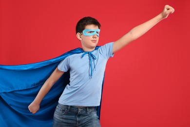 Teenage boy in superhero costume on red background