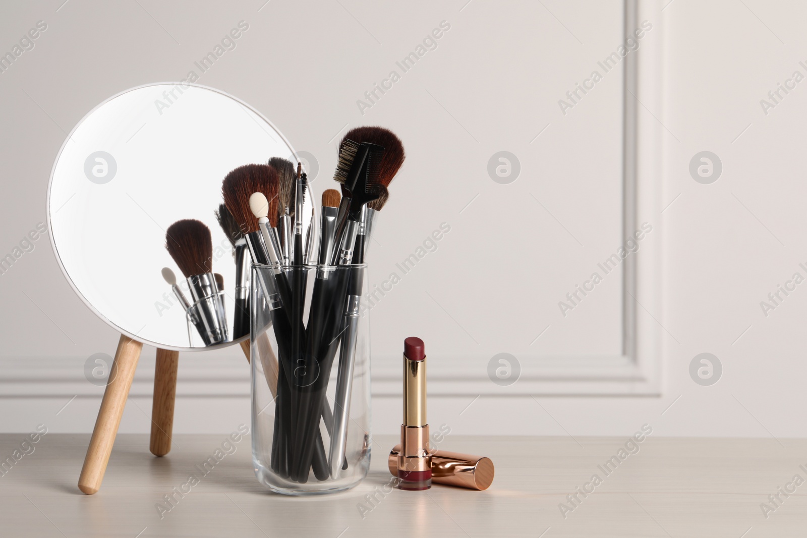 Photo of Set of professional brushes, lipstick and mirror on wooden table indoors, space for text