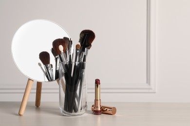 Set of professional brushes, lipstick and mirror on wooden table indoors, space for text