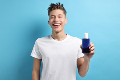 Photo of Young man with mouthwash on light blue background