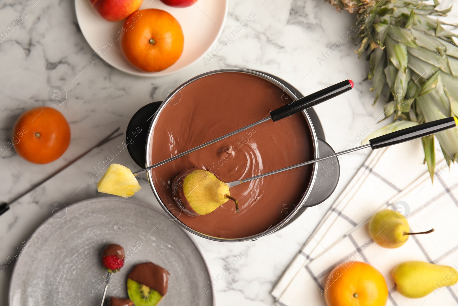 Photo of Flat lay composition with chocolate fondue in pot and fruits on marble background