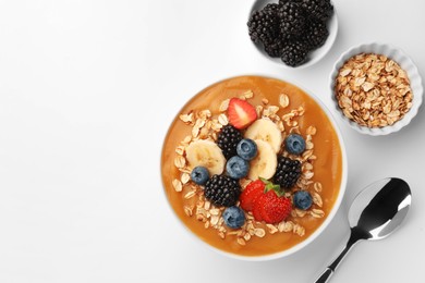 Delicious smoothie bowl with fresh berries, banana and oatmeal on white background, flat lay. Space for text