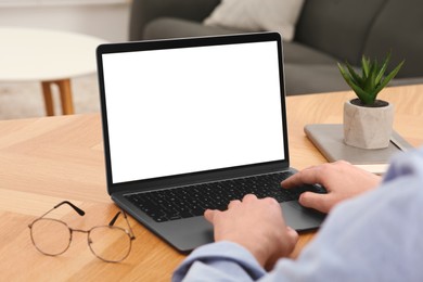 Photo of Man working with laptop at wooden table indoors, closeup