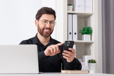 Photo of Smiling man in shirt using smartphone in office