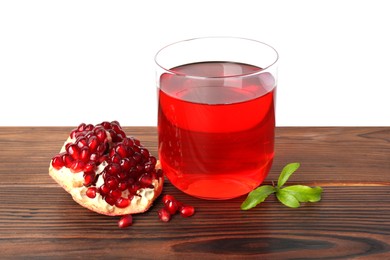 Photo of Refreshing pomegranate juice in glass, leaves and fruit on wooden table against white background