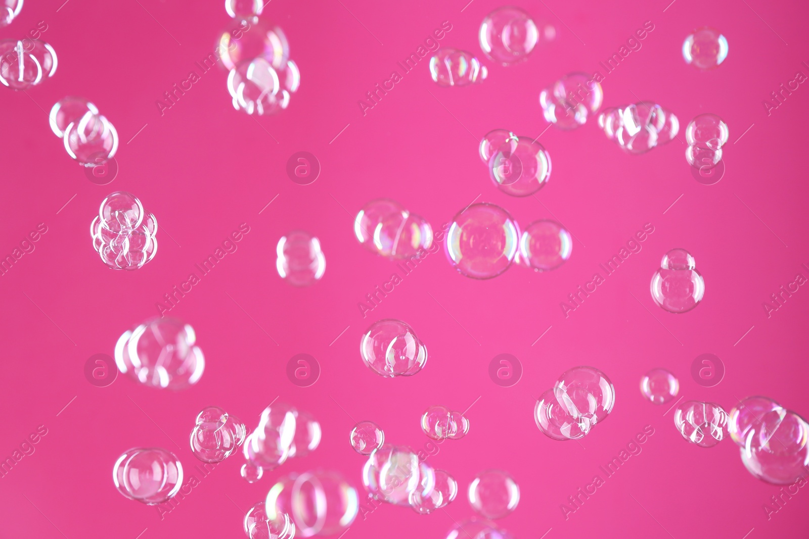 Photo of Beautiful transparent soap bubbles on pink background