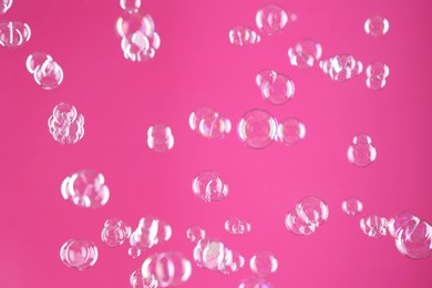 Photo of Beautiful transparent soap bubbles on pink background