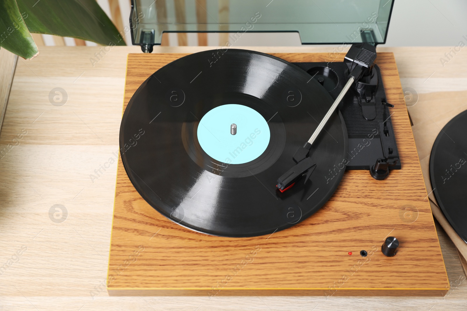 Photo of Stylish turntable with vinyl disc on light wooden table indoors