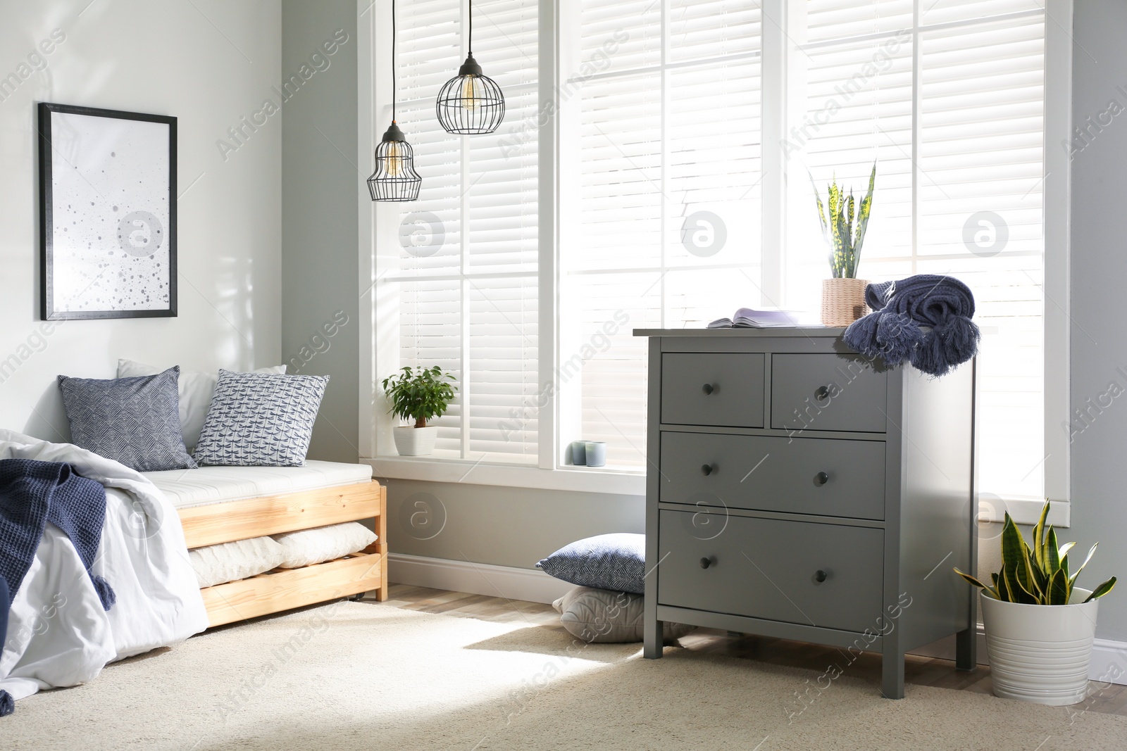 Photo of Grey chest of drawers near window in stylish bedroom interior