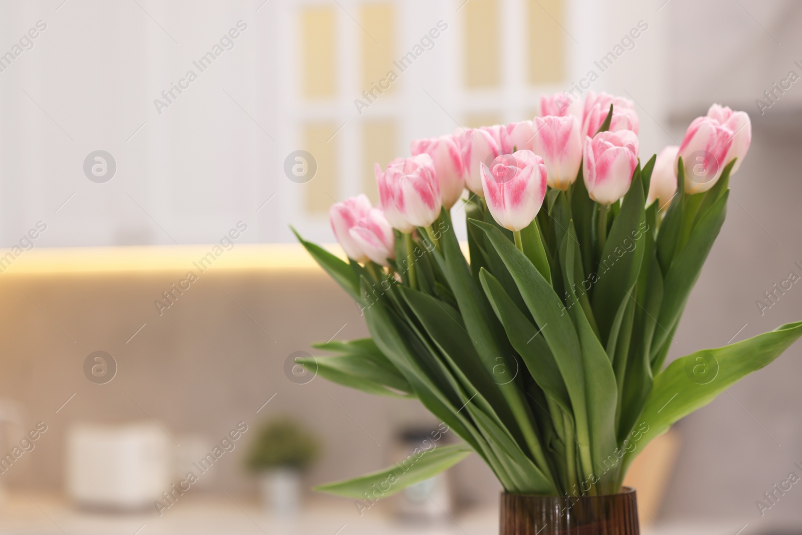 Photo of Beautiful bouquet of fresh pink tulips in kitchen. Space for text